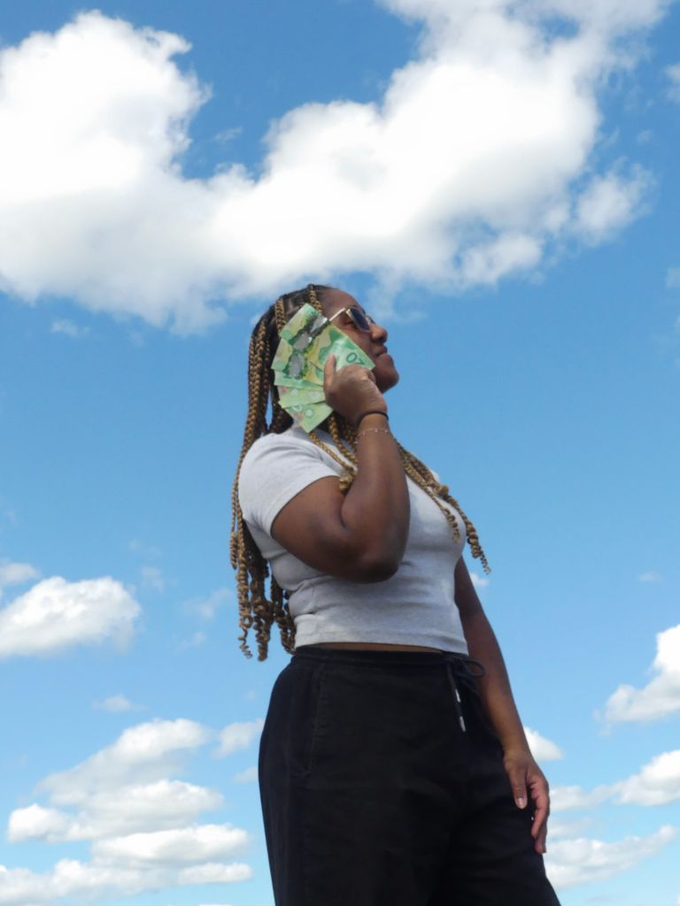 Woman with money fan against sky